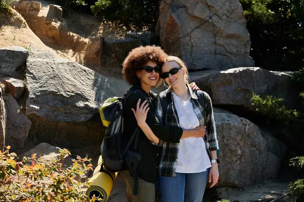 stock image A young lesbian couple embraces amidst a rocky landscape during a hike.