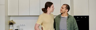 A young gay couple shares a moment in their modern kitchen, enjoying a quiet conversation in their cozy apartment. clipart