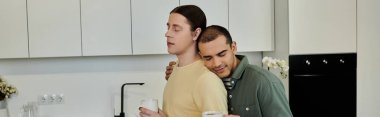 İki genç adam modern apartman mutfağında bir anlık yakınlık paylaşıyor..
