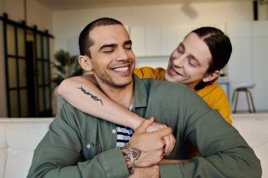 Genç eşcinsel bir çift modern dairelerinde sevgi dolu bir kucaklaşmayı paylaşıyor..