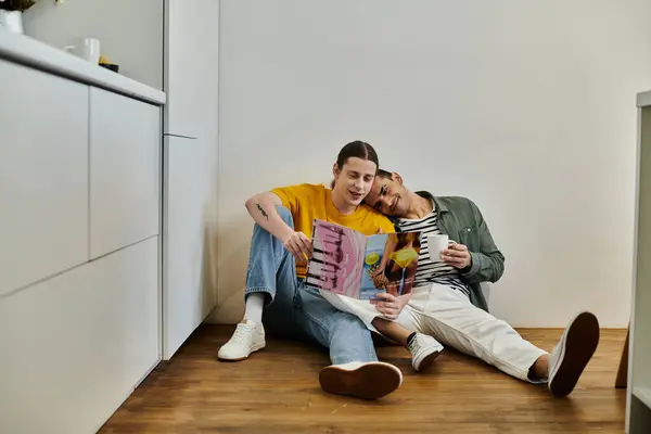 stock image A young gay couple relaxes in a modern apartment, sharing a moment of intimacy while reading a magazine.
