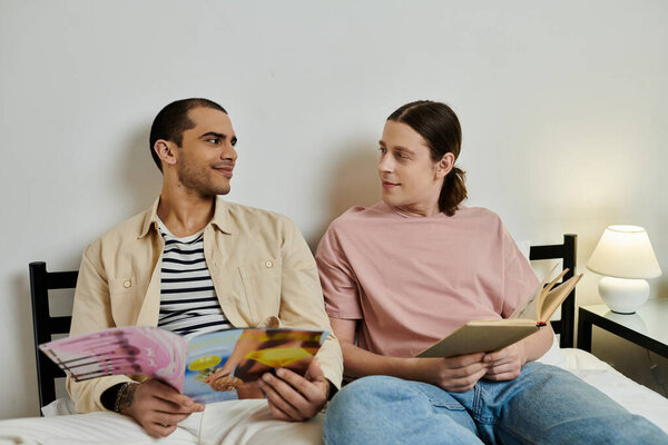 A young gay couple relaxes on a bed in a modern apartment, sharing a cozy moment together.