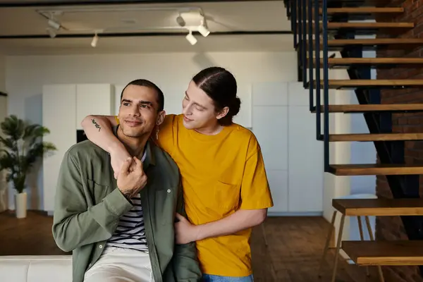 Stock image A young gay couple in casual attire enjoys quality time in a modern apartment with a wooden staircase.