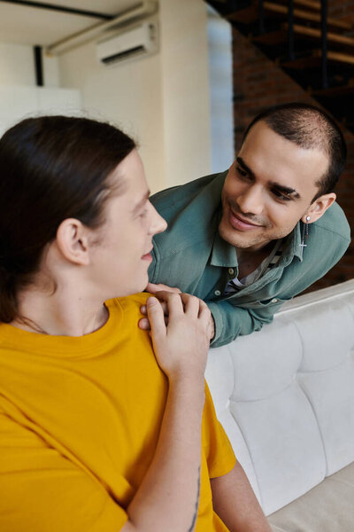 A young gay couple shares a tender moment in their modern apartment.