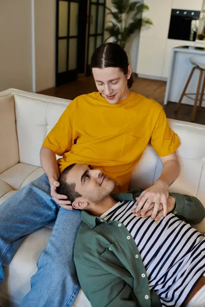 stock image A young gay couple shares a tender moment of intimacy on a couch in a modern apartment.