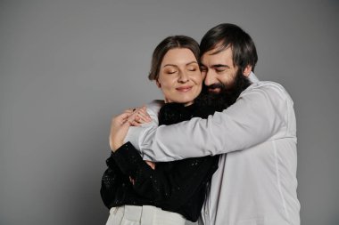 Sofistike giyinmiş sevgi dolu bir çift bir portre için poz verir, birbirlerine şefkatle sarılırlar..