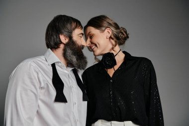 Sofistike giyinmiş, sevgi dolu bir çift gri bir arkaplana karşı bir portre için poz veriyor..