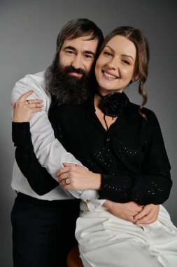 Sevgi dolu bir çift, şık giyinmiş olarak birlikte poz verir..