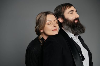 Resmi giyinmiş bir çift, sevgi ve zarafet göstererek kucaklaşır..