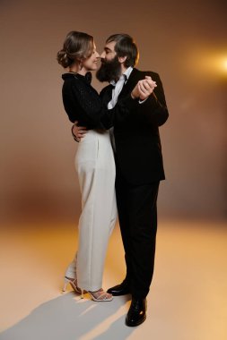 A loving couple, dressed in elegant attire, poses for a studio portrait. clipart