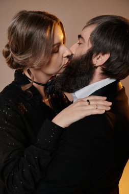 Siyah elbiseli, sevgi dolu bir çift, bir portre için poz verir, bir yakınlık anını yakalar..
