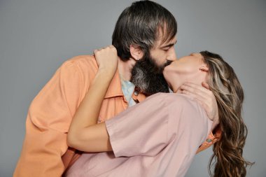 Sofistike giyinmiş sevgi dolu bir çift stüdyo ortamında sarılıp öpüşüyor..