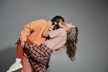 A man and a woman in stylish attire share a loving embrace, their affection evident in their joyful expressions. clipart