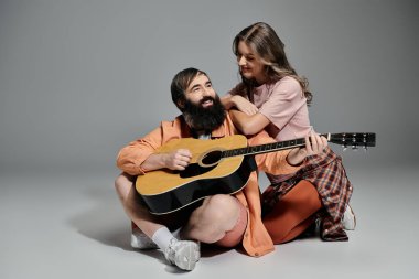 Kadın ve erkek birlikte poz verir, erkek gitar çalarken kadın onu sevgiyle izler..