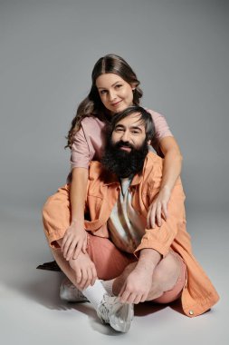 Sofistike giyinmiş sevgi dolu bir çift stüdyo ortamında birlikte poz veriyor..