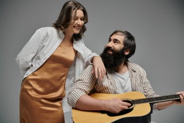 Bir çift birlikte poz veriyor, gitar çalan adam, kadına sevgiyle bakıyor..