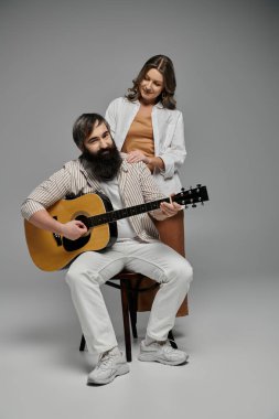 Stüdyoda gitar çalan adamla şık giyinmiş, sevgi dolu bir çift..