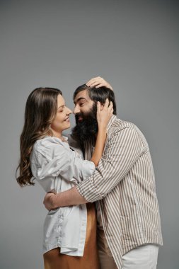 Sofistike giyinmiş bir kadın ve erkek birbirlerine yakın dururlar, birbirlerine sevgiyle bakarlar..