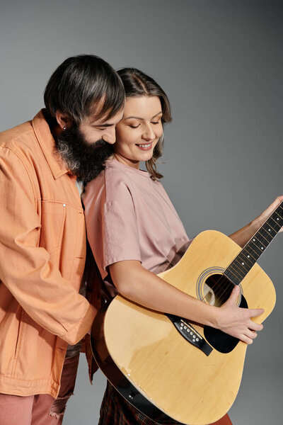 A couple poses together, the woman holding a guitar.