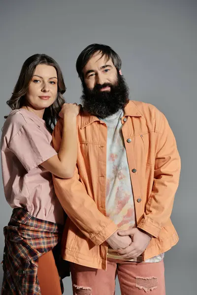 stock image A loving couple poses together in casual attire, wearing peach-toned clothing.