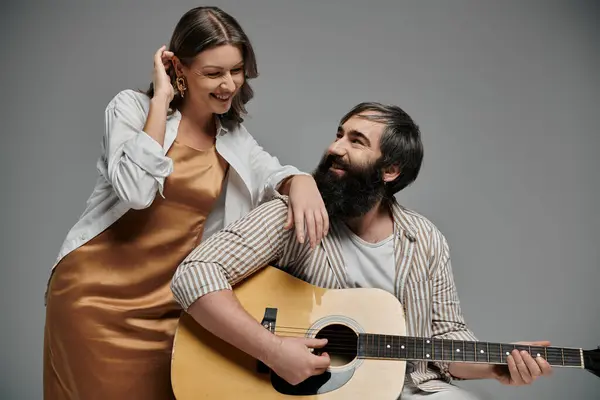 stock image A man plays the guitar while a woman smiles at him.