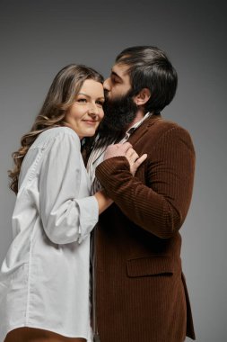 Kahverengi kadife ceketli bir adam beyaz gömlekli bir kadının alnını öpüyor..