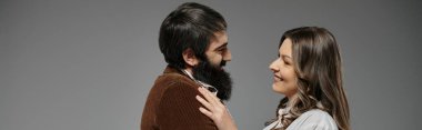 Sofistike giyinmiş bir çift birbirine sevgiyle bakıyor, samimi ve romantik bir portre yaratıyorlar..
