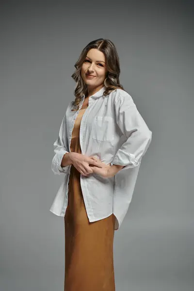 stock image A woman in a white shirt and brown skirt poses against a gray backdrop.
