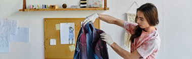 Genç bir adam DIY giysi restorasyon atölyesindeki bir giysiyi titizlikle inceliyor, sürdürülebilirlik tutkusunu gösteriyor ve eski eşyalara yeni bir hayat veriyor..