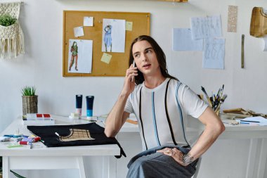 DIY giysi restorasyon atölyesi sahibi genç bir adam stüdyosunda bir proje üzerinde çalışırken telefonla konuşuyor..