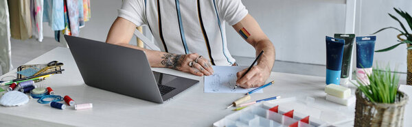 A young gay man works on a design at his DIY clothing restoration atelier. He focuses on sustainability by giving new life to discarded clothing.