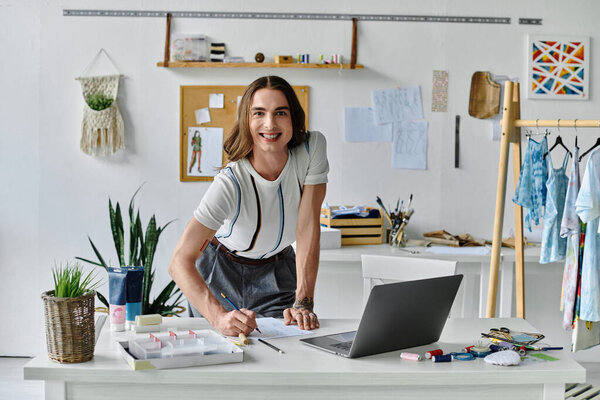 A young gay man smiles as he works on a clothing restoration project in his atelier.