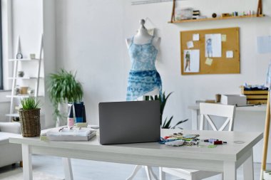 Üzerinde dizüstü bilgisayarı, mankeni ve çeşitli aletleri olan DIY giysi restorasyon atölyesinde beyaz bir masa..