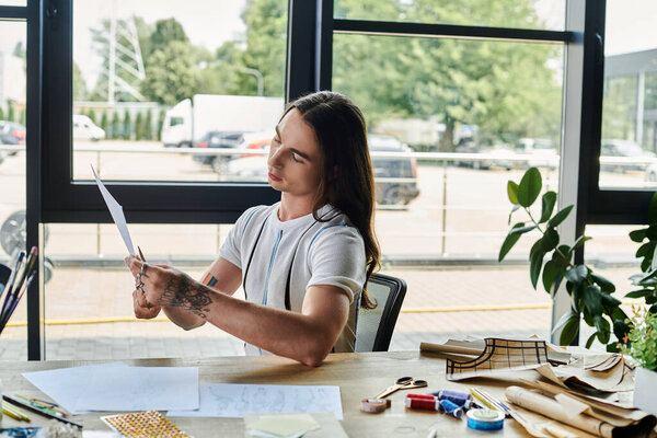 A young gay man meticulously reviews a pattern in his DIY clothing restoration atelier, dedicated to giving new life to discarded garments.