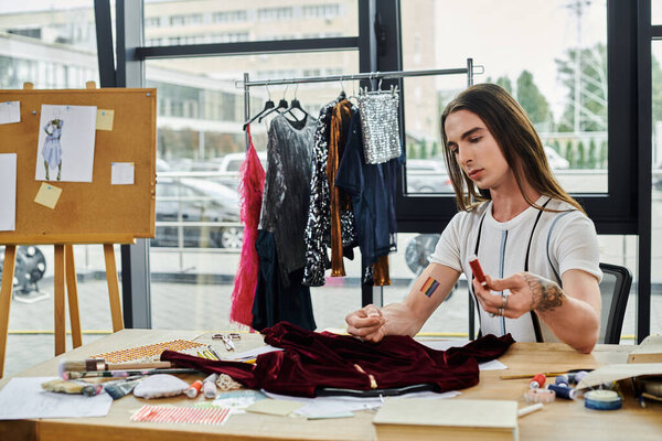 A young gay man carefully examines a piece of fabric in his clothing restoration atelier, focusing on giving new life to discarded garments.