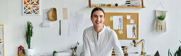 A young man smiles warmly as he stands in his DIY clothing restoration atelier.