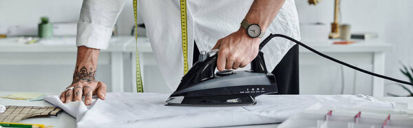 A young man in a white shirt uses an iron to give new life to discarded clothing.