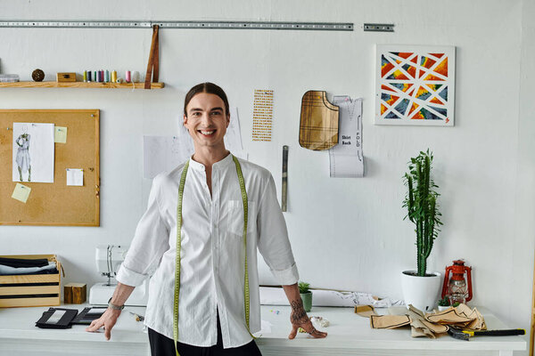 A young man smiles confidently in his DIY clothing restoration atelier, showcasing his passion for sustainable fashion and giving new life to old clothes.
