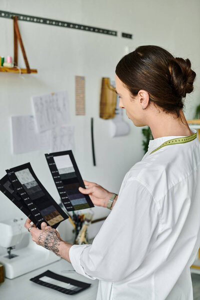 A young man meticulously examines fabric swatches in his clothing restoration atelier, showcasing his dedication to sustainable fashion.
