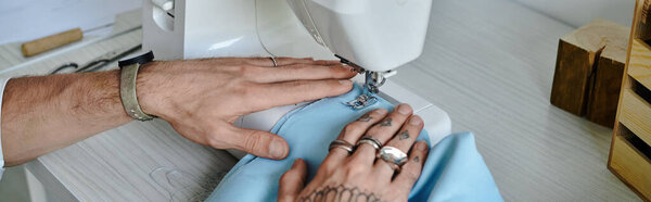 A young man in a white shirt sews a blue fabric on a sewing machine, focusing on sustainable clothing restoration.