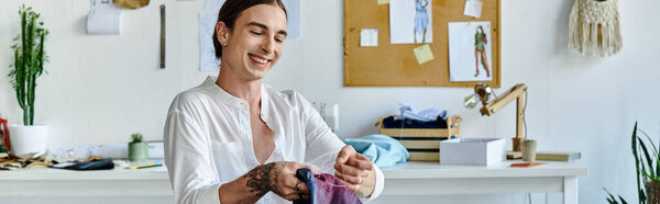 A young tailor smiles while examining fabrics in his DIY clothing restoration atelier.