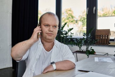 Kapsamlı bir adam masasında oturmuş, dikkatle bir telefon konuşmasını dinliyor..