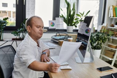 Modern bir ofiste masa başında çalışan ve belgeleri incelemeye odaklanmış bir adam..