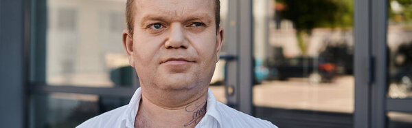 A man with inclusivity pauses in front of a glass door, his gaze focused on something beyond the frame.