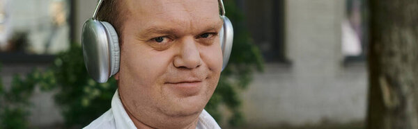 A man with inclusivity wearing headphones walks outdoors.