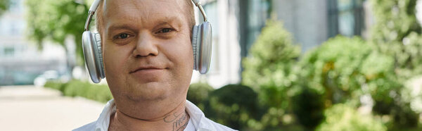 A man with inclusivity walks in a city setting, lost in his own world while listening to music through headphones.