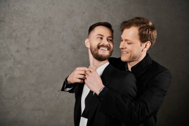 Takım elbiseli iki adam birbirine sarılıp gülüyor, yüzleri neşeyle dolu..