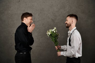 Takım elbiseli eşcinsel çift, beyaz çiçekli olan, romantik anı paylaşır.