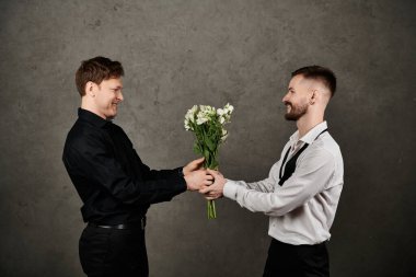 Zarif takım elbiseli eşcinsel bir çift bir buket beyaz çiçeği değiş tokuş ediyor..