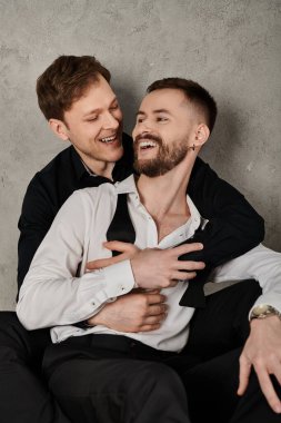 A loving gay couple in elegant suits embraces and laughs together. clipart